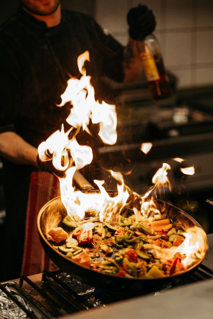 Chef cooking vegetables over an open flame